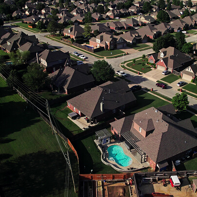 Aerial view of a suburban neighborhood with houses and a backyard pool.