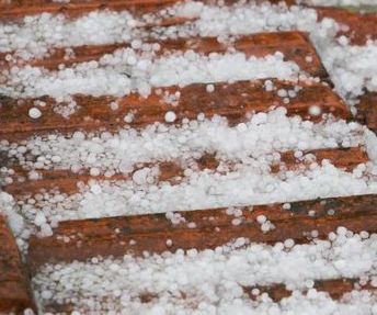 Close-up of hailstones covering wooden stairs after a storm.